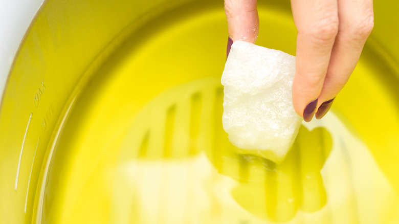 Manicurist melts paraffin in a paraffin bath