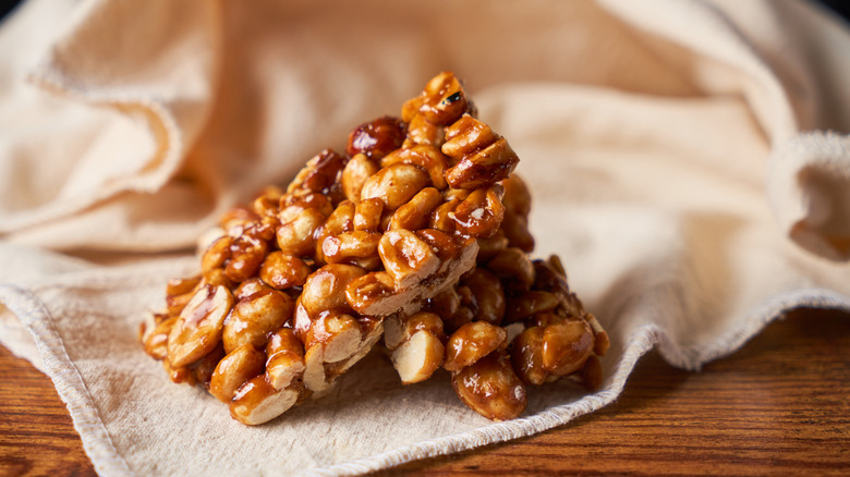 Peanut brittle candy stacked on top of beige cloth