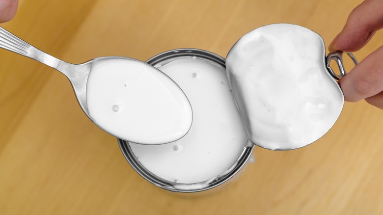 Open can of coconut milk with a spoon