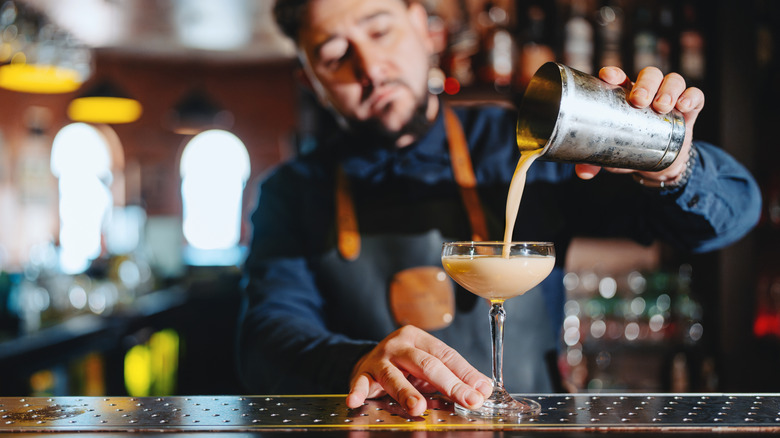 Bartender pouring a daiquiri cocktail from the cocktail shaker