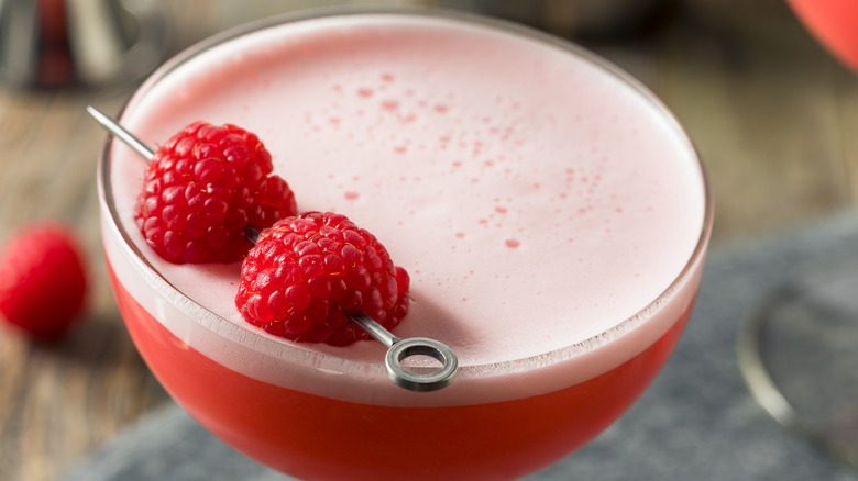 Aerial close-up of Clover Club cocktail with raspberry garnish and thick pink foam