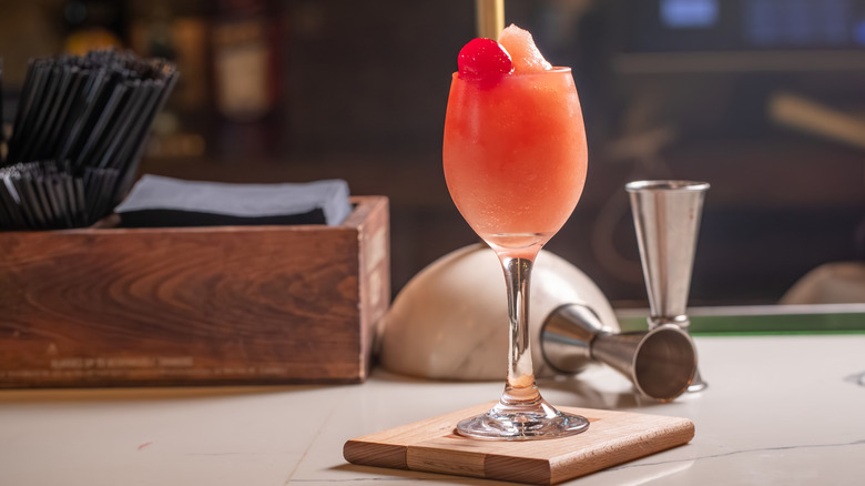 Frozen rosé in a wine glass against dimly lit bartop with some bar accessories in the back