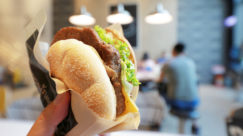 Hand holding a Cheesy Champignon Angus Burger In a McDonald's in Taiwan
