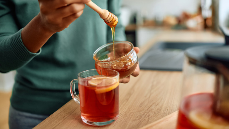 Close up of woman putting honey in her tea