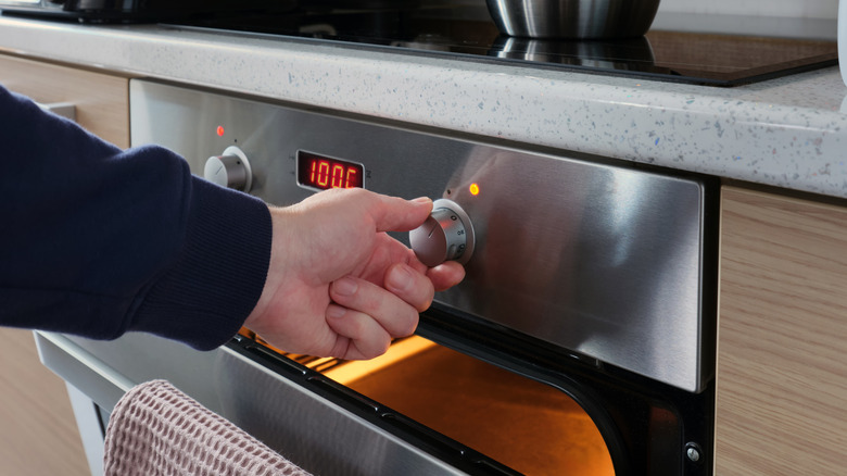 hand adjusting the oven temperature