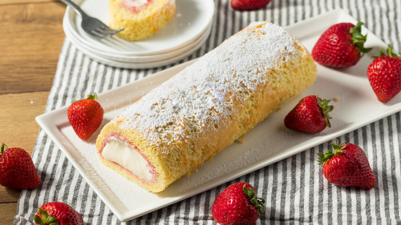 Frozen Arctic roll cake dusted with powdered sugar and served with fresh strawberries