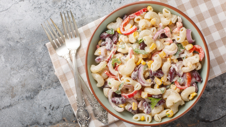 Bowl of creamy pasta salad with red bell pepper, corn, and red onion