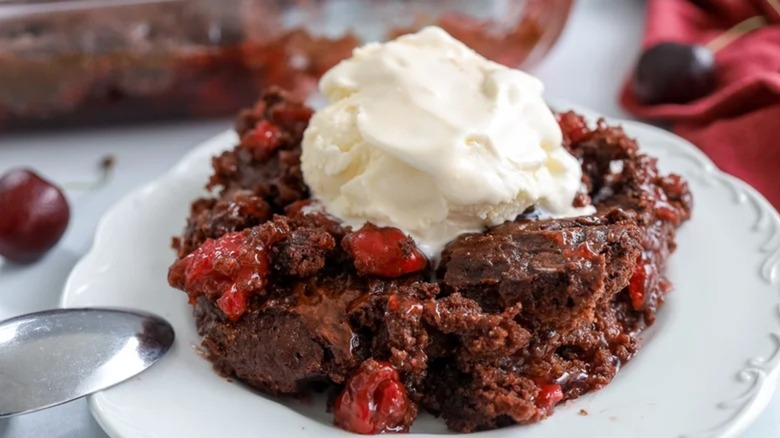 Cherry cola dump cake on a plate with ice cream on top and a spoon