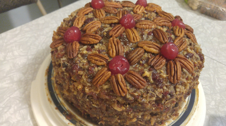 Lane cake on platter with pecans and cherries on top in the shape of flowers