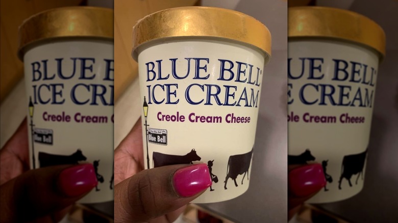 Hand holding pint of Blue Bell Creole Cream Cheese ice cream