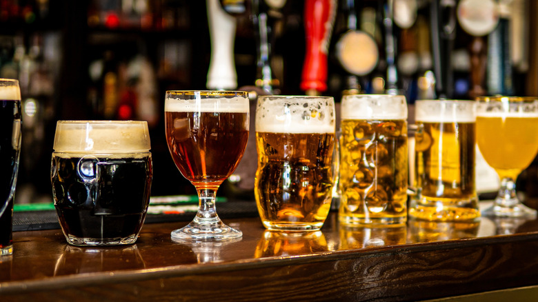 A bar counter with a variety of different types of beers in glasses