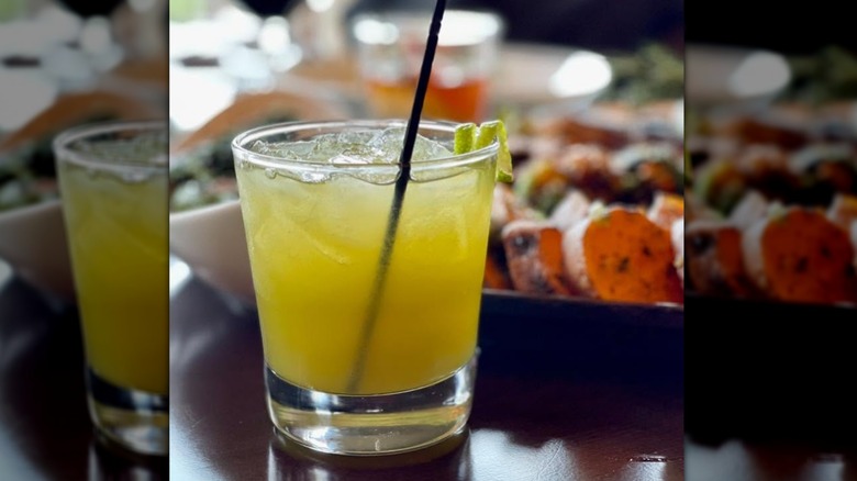 A honey badger cocktail in a glass with food in the background
