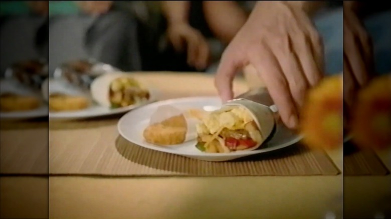 Hand reaching for McDonald's McSkillet Burrito on plate