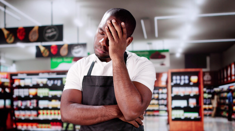 Stressed grocery store employee looking sad