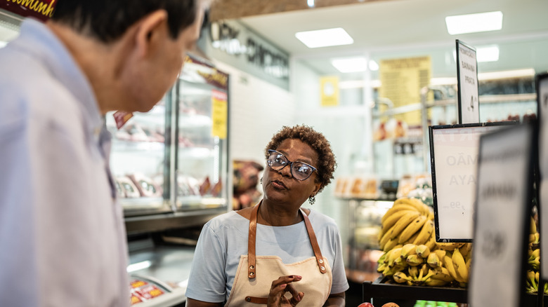Employee helping customer at self-checkout in a grocery store