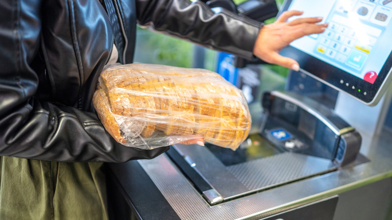 Customer scanning bread at self checkout kiosk