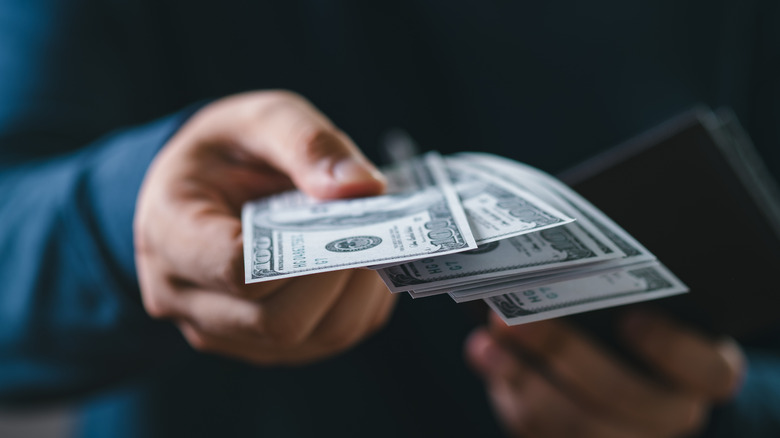 Person handing over dollar bills