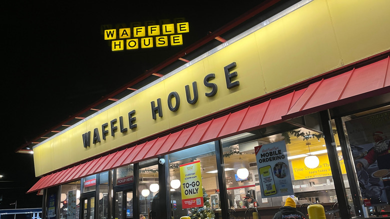 The exterior of a Waffle House is pictured with a "To-Go Only" poster and a "Mobile Ordering" poster affixed to the store windows.