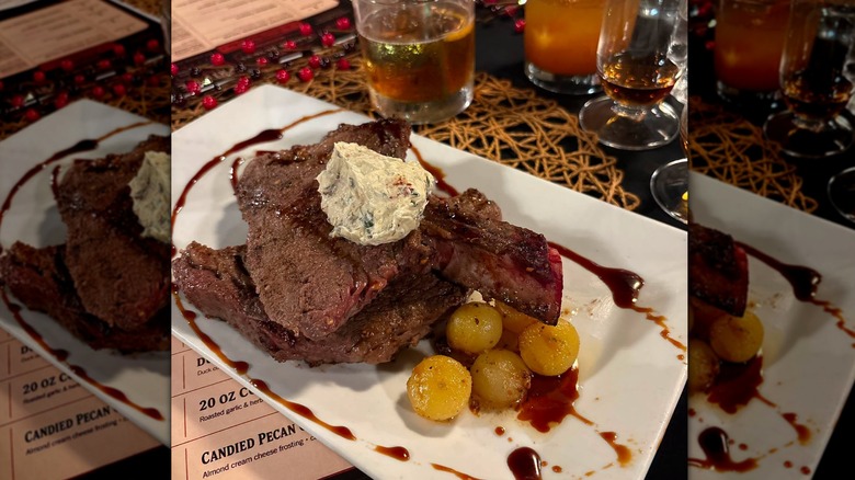 Decadent plate of steak topped with a compound butter beside a number of cocktails