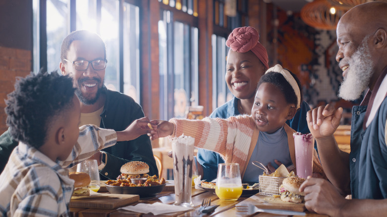 Family of varied ages gathered around a restaurant table eating food