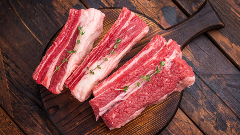 Raw beef short ribs on round wooden cutting board