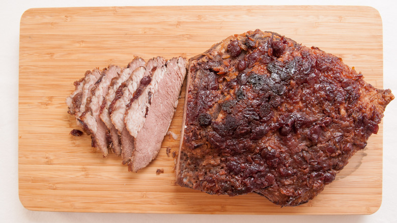 Braised brisket being sliced on wooden cutting board