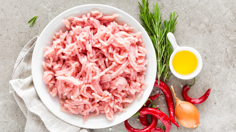 Ground chicken in white bowl next to various ingredients