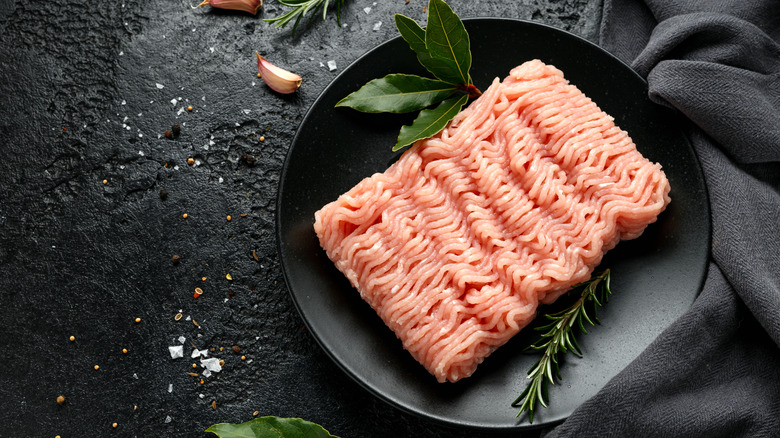 Raw turkey on black plate with herbs