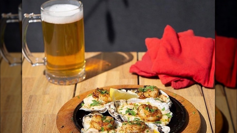 Plate of oysters and a mug of beer on wooden table
