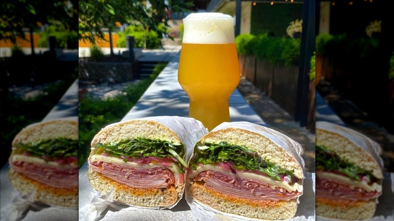 Two halves of a sandwich with beer sitting outside on sunny day