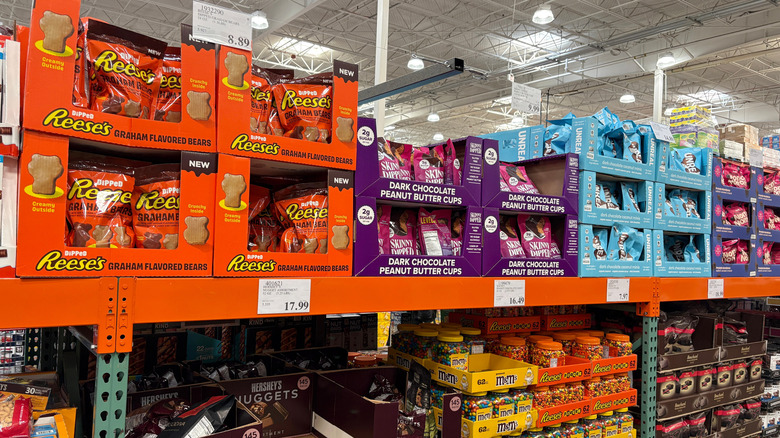 A close up of a shelf full of tubs of M&Ms.