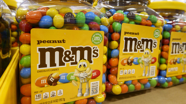 A close up of three 62-ounce tubs of peanut M&M's.