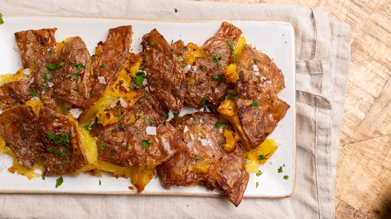 air-fried garlic smashed potatoes on a white dish over a cloth
