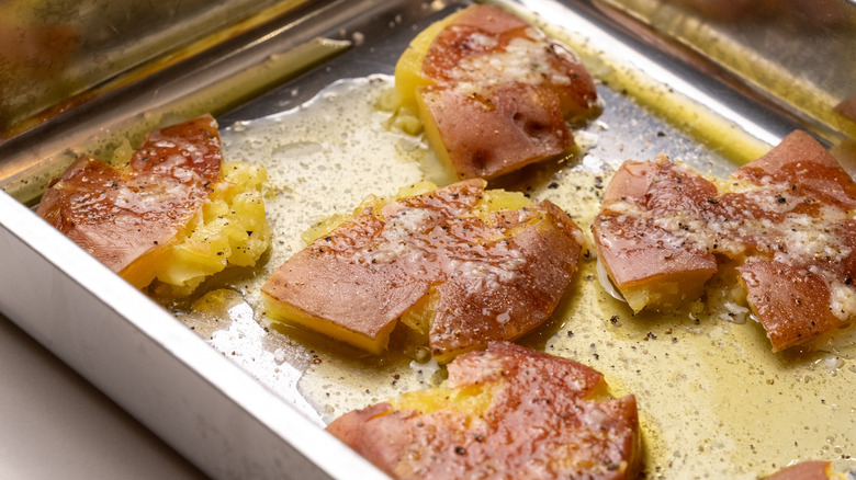 seasoned smashed potatoes in tray with garlic butter