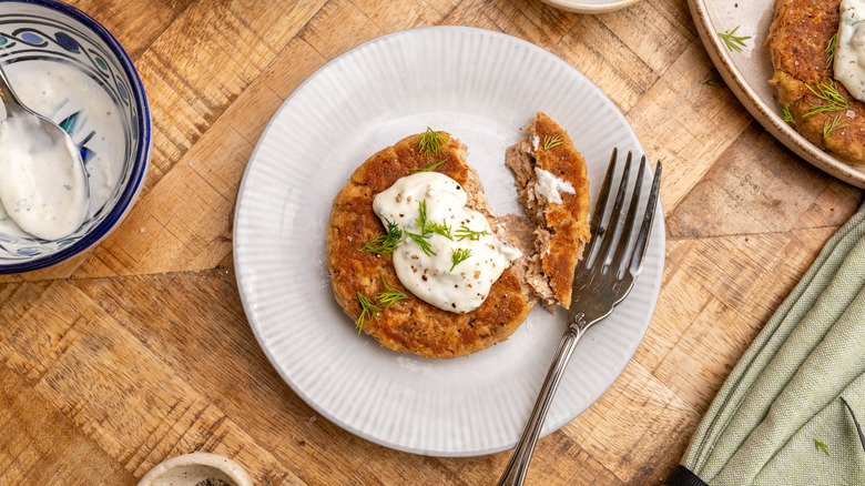 Tuna patty with creamy sauce and fork on plate
