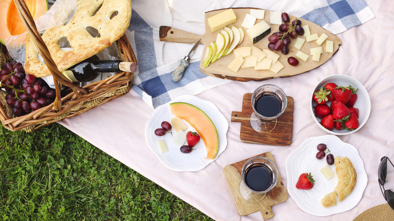 An aerial view of a picnic spread with strawberries, cheese, fruit, and wine