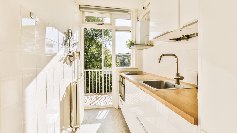 Sunlight streams through a small cream-colored kitchen.