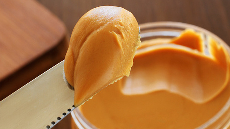 Butter knife scooping peanut butter out of container