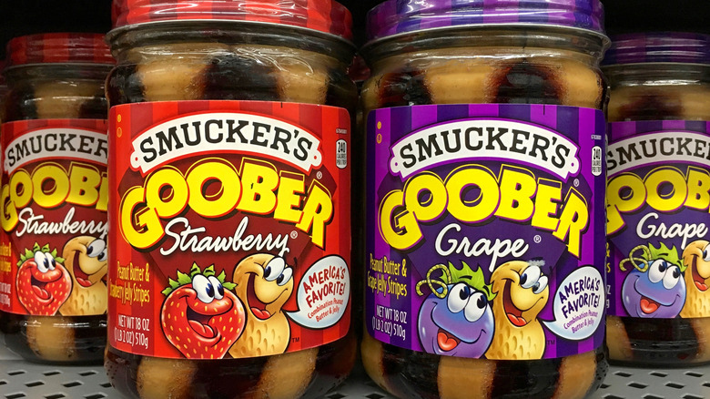 Two jars each of strawberry and grape Smucker's Goober on grocery store shelf