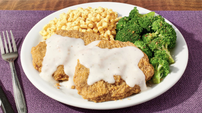 Denny's chicken fried steak with broccoli and corn on a white plate