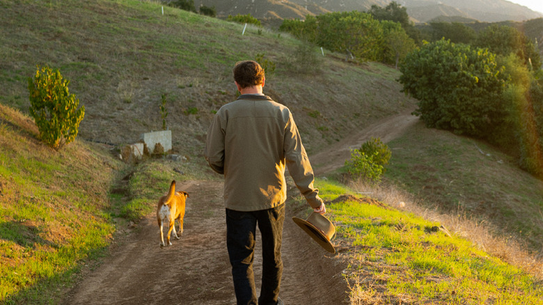 Co-Founder Jay Ruskey walks through a coffee farm with a dog.