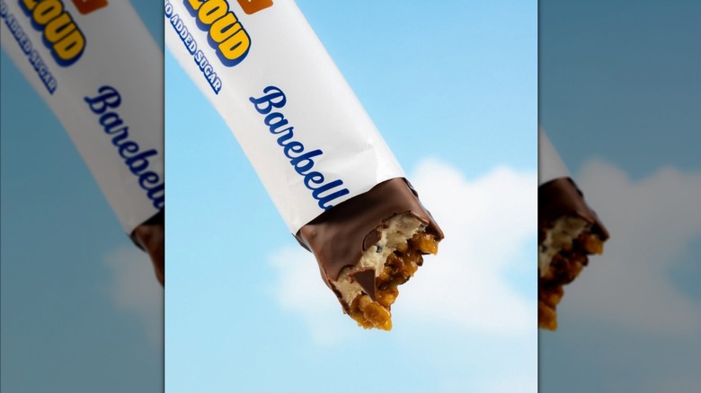 Barebells protein bar with bite taken out against blue sky background