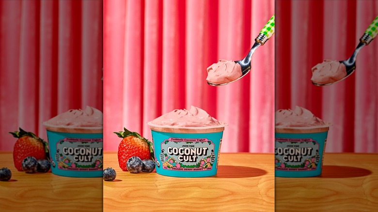 Spoon taking yogurt from Coconut Cult container next to berries