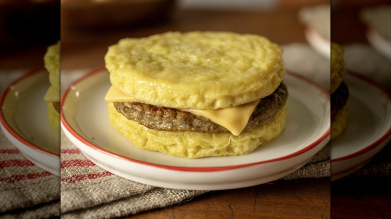 Red's sausage and cheese breakfast sandwich made with egg patties instead of bread, served on a plate