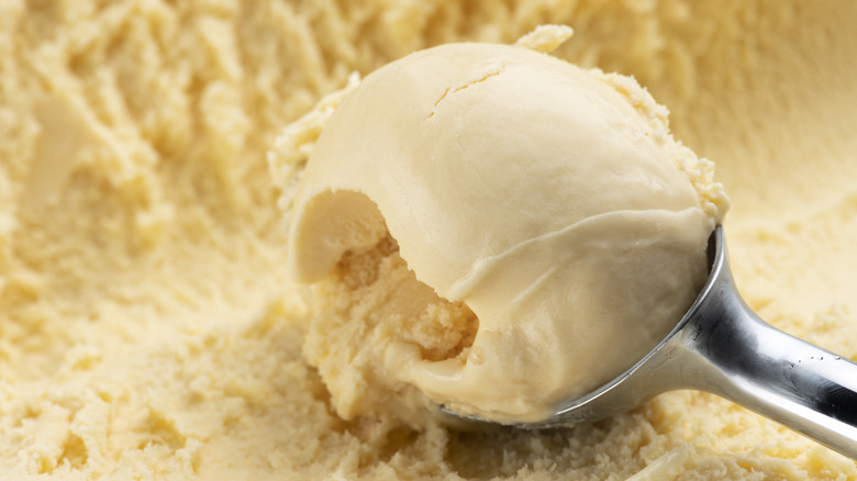 Vanilla ice cream being scooped with silver ice cream spoon