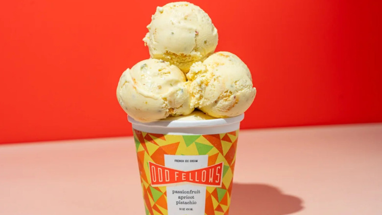 Carton of passionfruit apricot pistachio ice cream with three scoops on top