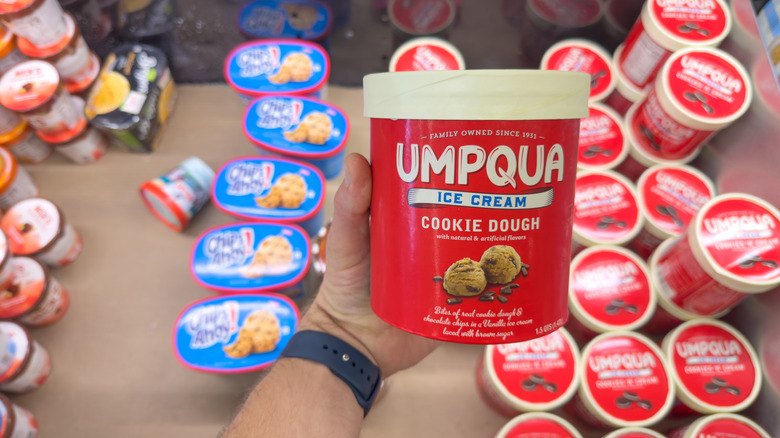 Hand holding carton of Umpqua cookie dough ice cream in grocery store