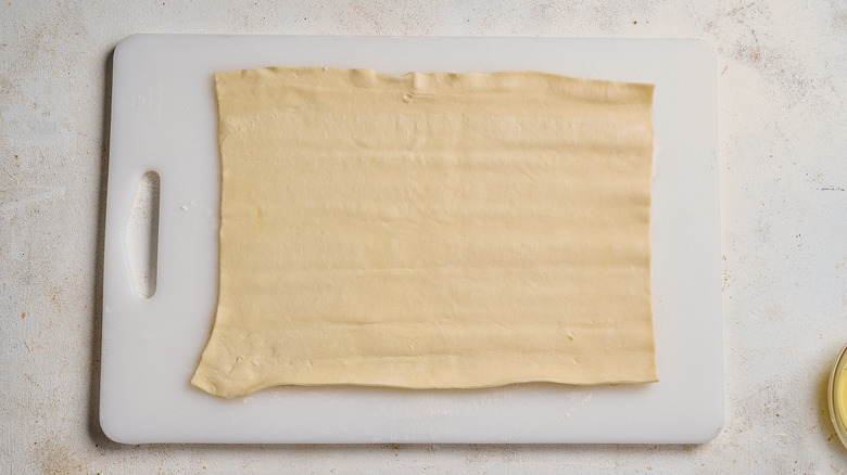 Rolling out puff pastry on a cutting board