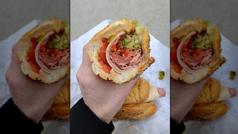 Hand holding Italian sub sandwich from P&K Delicatessen