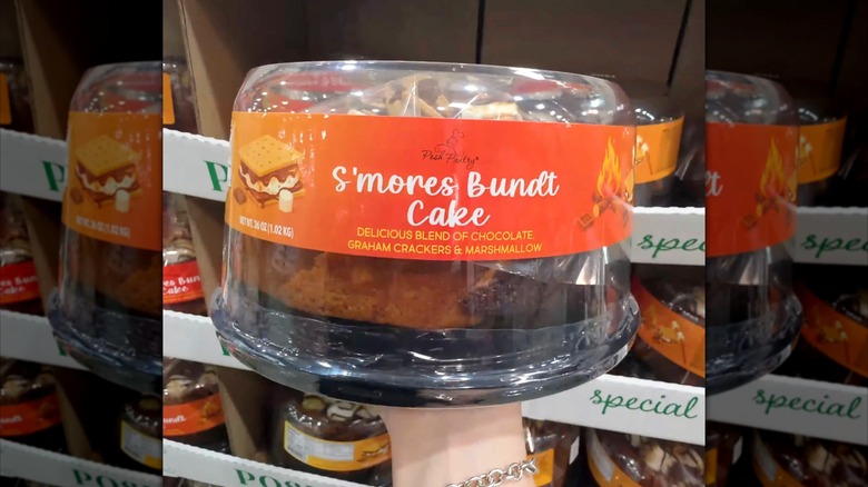 Hand holding Jean's Posh Pantry S'mores Bundt Cake inside Costco store